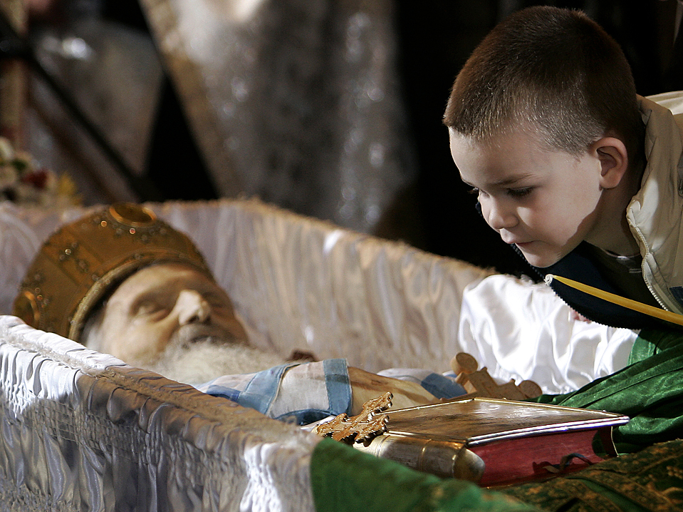 A boy reacts near the coffin of Patriarch Pavle as he lies in repose at the Congregational church, in Belgrade, Serbia, Tuesday, Nov. 17, 2009. Patriarch Pavle, who led Serbia's Christian Orthodox Church through its post-Communist revival and called for peace and conciliation during the Balkan conflicts of the 1990s, died Sunday. (AP Photo/Darko Vojinovic)